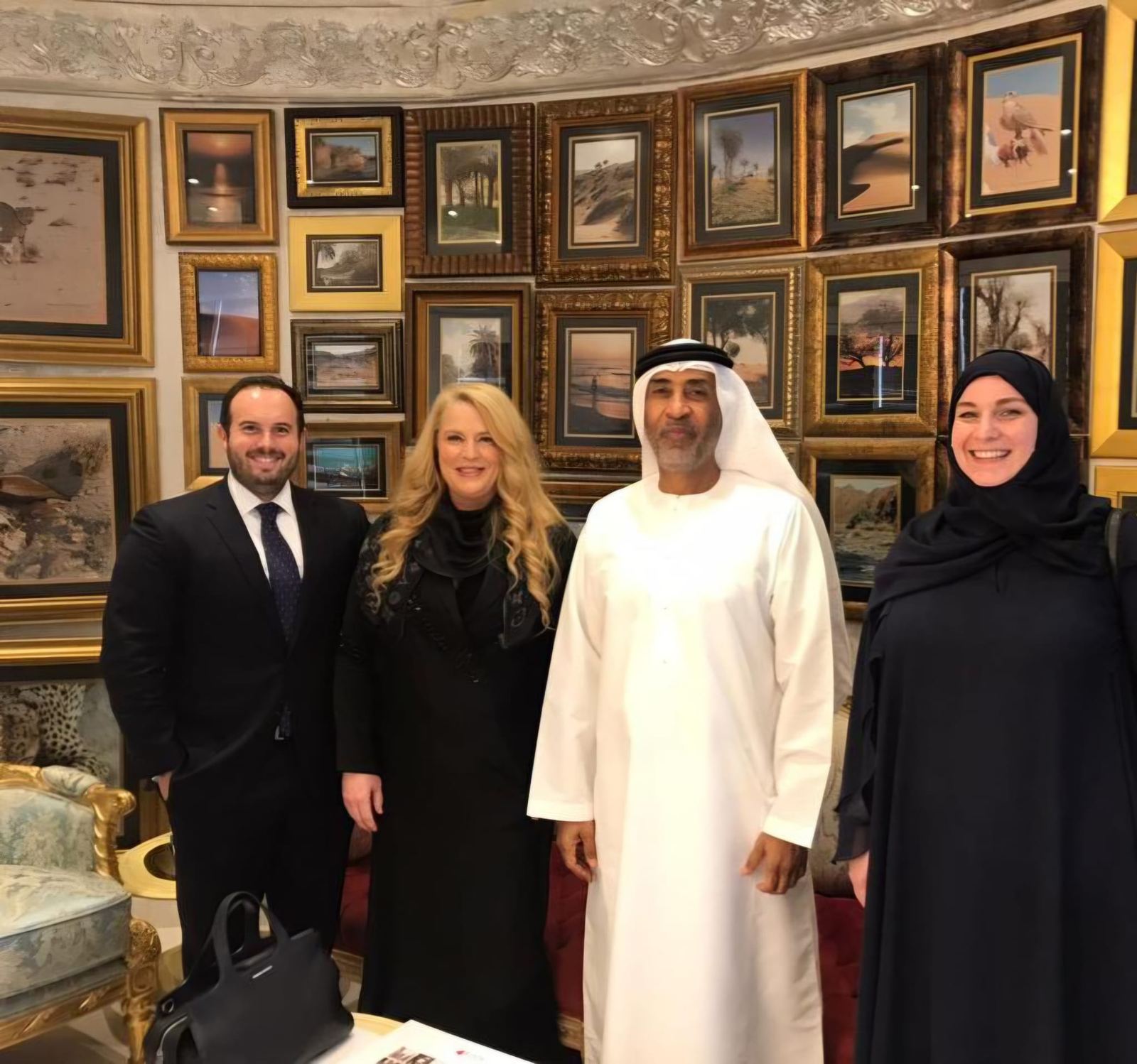 Guild members with hosts in a majlis lined with framed paintings